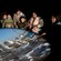 Adults and children around a camera obscura as a guide points out city buildings in its projected image